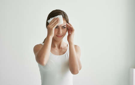woman wiping her face with a handkerchief feeling unwell health coldの写真素材