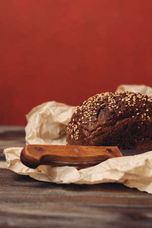 rye bread on paper packaging on a red background and a wooden table with a sharp knife