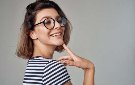 portrait of a happy blonde in a striped t-shirt and his glasses on a gray background