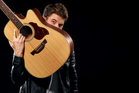 A man with a guitar in his hands leather jacket music performance rock star modern style dark backgroundの写真素材