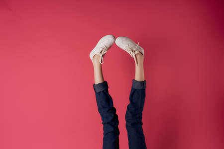 Inverted female legs white sneakers motion street style red background