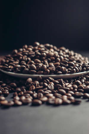 saucer with coffee beans and white cup on gray table close-up