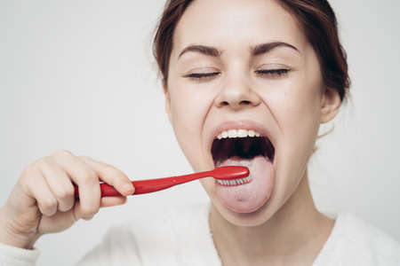 pretty woman in white robe brushing tongue hygieneの写真素材