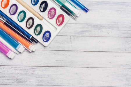 watercolor paint markers and pencils on a wooden table top view Copy Space
