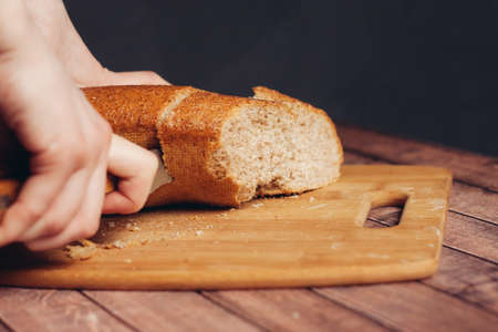 slicing a loaf on a wooden cutting board freshnessの写真素材