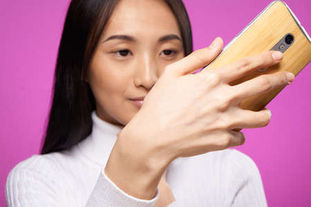 woman asian appearance phone in hands close-up technology gadget pink backgroundの写真素材