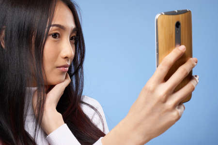 woman of asian appearance with phone in hands communicating internet lifestyle technology