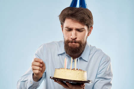 cake in a plate and birthday man with a cap on his head blue backgrounの写真素材