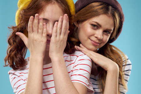 Girl in a yellow beret and a woman on a blue background mom and daughterの写真素材