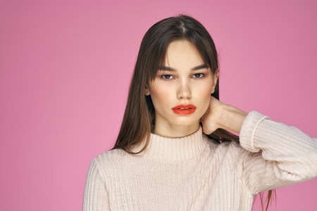 Pretty brunette in a white sweater red lips attractive look pink backgroundの写真素材