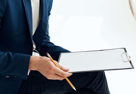 Business man in a suit with documents writes down important informationの写真素材