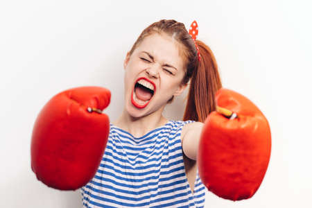 woman in boxing gloves and in a striped T-shirt screaming aggression stressの写真素材