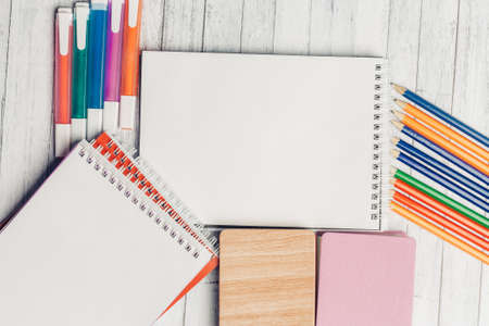 notepad colored pencils stickers markers on wooden tableの写真素材