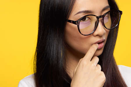woman of asian appearance glasses attractive look holds finger on lipsの写真素材