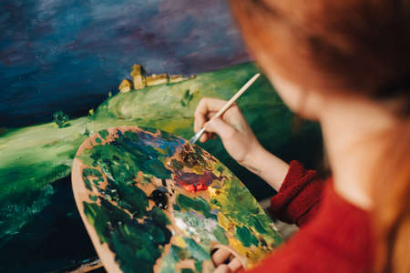 the artist paints a picture on an easel palette imageの写真素材