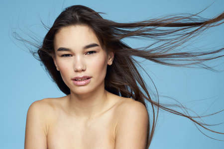pretty brunette naked shoulders long hair skin care blue backgroundの写真素材
