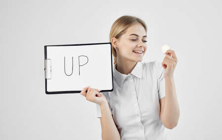 cheerful woman in a white shirt holds a folder with the inscription upward cryptocurrency Bitcoin internet Finlandの写真素材