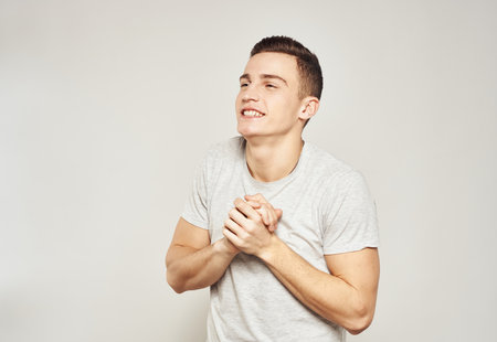Cheerful handsome man in T-shirt emotions gestures with hands light background