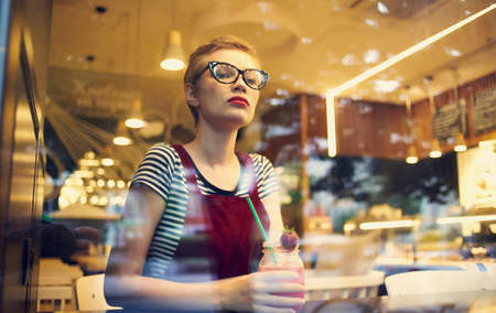 fashionable woman in red sundress resting in a cafe with a drinkの写真素材