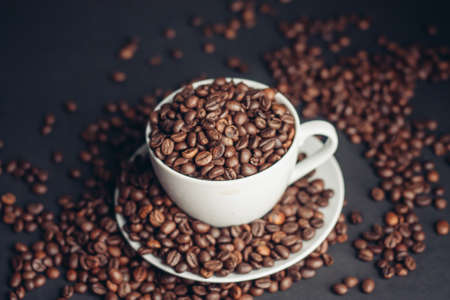 coffee beans In a saucer and in a cup of coffee on a gray background female hand macro photographyの写真素材