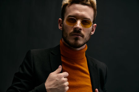 beautiful blonde with glasses and an orange sweater black jacket gesturing with his hands dark background Copy Spaceの写真素材