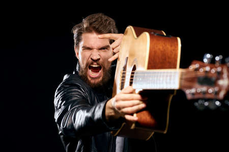 A man with a guitar in his hands leather jacket music performance rock star modern style dark...