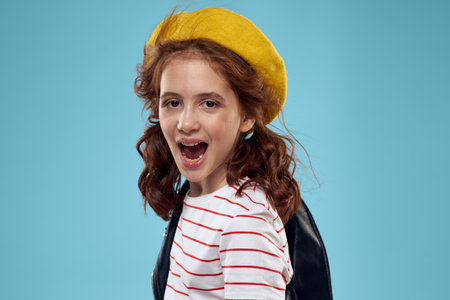 Fashionable girl in a black jacket with a yellow ticket striped T-shirt blue background