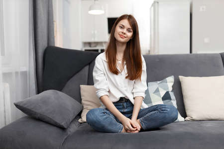 woman sitting on the couch bending her knees at home in an apartment restの写真素材