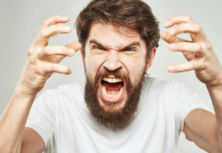 Aggressive man yells against a light background and gestures with his hands cropped viewの写真素材