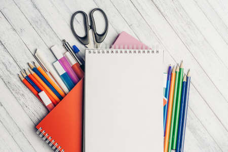 notepad colored pencils and markers pens on wooden table at school office