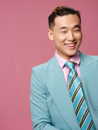 man of Asian appearance blue suit self confidence pink backgroundの写真素材