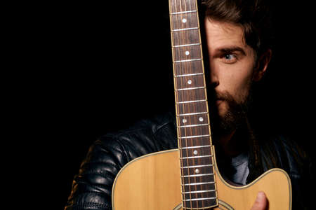 A man with a guitar in his hands leather jacket music performance rock star modern style dark...