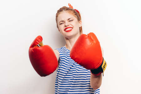 aggressive woman boxing on a light background in a striped t-shirt and red gloves cropped viewの写真素材