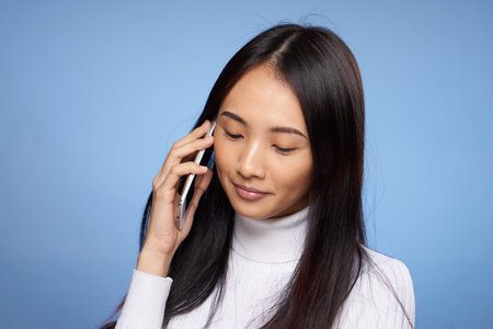 woman of asian appearance talking on the phone technology blue backgroundの写真素材