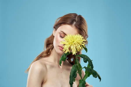 beautiful woman with yellow flower near face smiling cropped view portrait of bared shoulders