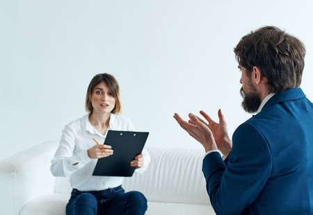Business man in a classic suit and a woman on the couch with documents in the hands of a psychologistの写真素材