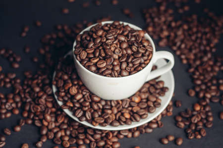 coffee beans In a saucer and in a cup of coffee on a gray background female hand macro photographyの写真素材