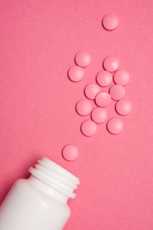 Open jar with pills on pink background coldspace top viewの写真素材