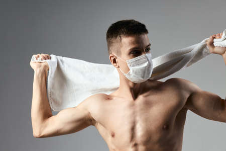 sport man wearing medical mask white towel in hands health safety workout close-upの写真素材