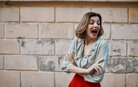 happy blonde girl with bright makeup near building gesturing with hands fashionable clothes style