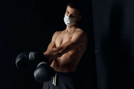 portrait of a boxer in a medical mask and black gloves on an isolated backgroundの写真素材