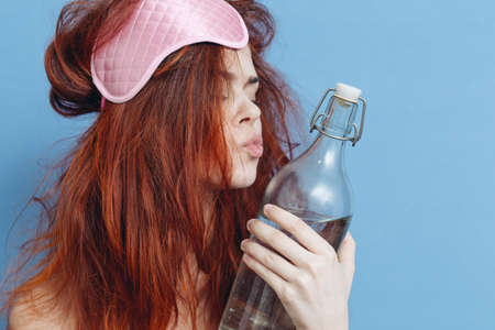 woman with red hair bottle alcohol hangover sleep maskの写真素材