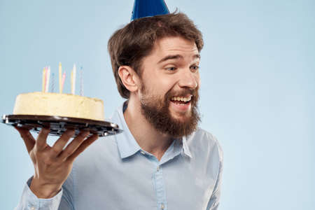 cake in a plate and birthday man with a cap on his head blue backgroun