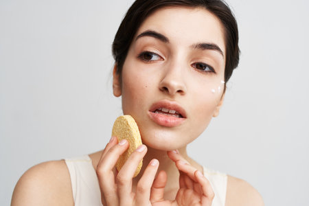 Pretty woman in white t-shirt Sponge in hands removing make-up clean skin