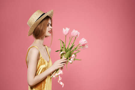 Woman golden dress holiday feminine gift flowers pink backgroundの写真素材