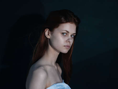 Woman with an interested look on a dark background side view modelの写真素材