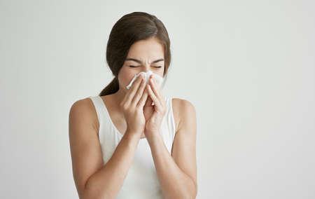 brunette in white t-shirt wipes her face with a handkerchief health problems coldの写真素材