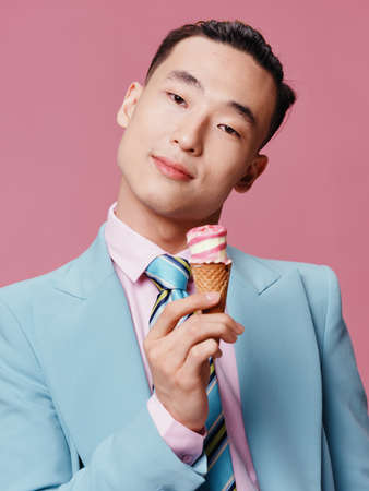 Cheerful man of Asian appearance ice cream smile close-up pink backgroundの写真素材