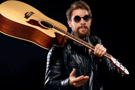 A man with a guitar in his hands leather jacket music performance rock star modern style dark backgroundの写真素材