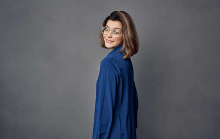 cheerful pretty woman with glasses blue shirt fashion gray backgroundの写真素材